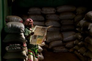 A man in traditional attire reads a newspaper in a dimly lit storeroom with stacked sacks. — Die aufregendsten Slot-Spiele im
