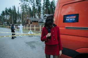 A reporter in red documents a crime scene with investigators in protective suits. — Spiele und Funktionen in der Royal Coala