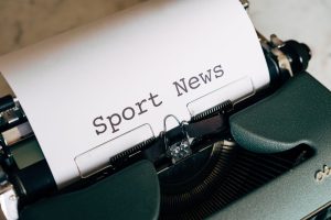 Close-up of a vintage typewriter with 'Sport News' typed on paper, evoking retro charm. — SupaBet Casino: Tu Carrera hacia Gr