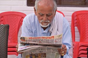 Elderly man engaging in daily reading of a newspaper while seated outdoors. — VIP Casino: Spielerfahrungen und Bewertungen