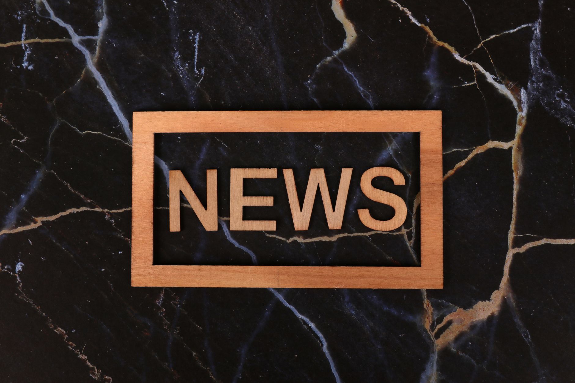 Wooden text of 'news' outlined on a dark, marbled surface, creating a striking contrast. — Winrolla Casino: Besondere Feature